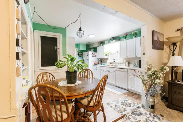 a kitchen with stainless steel appliances granite countertop a dining table chairs and a refrigerator