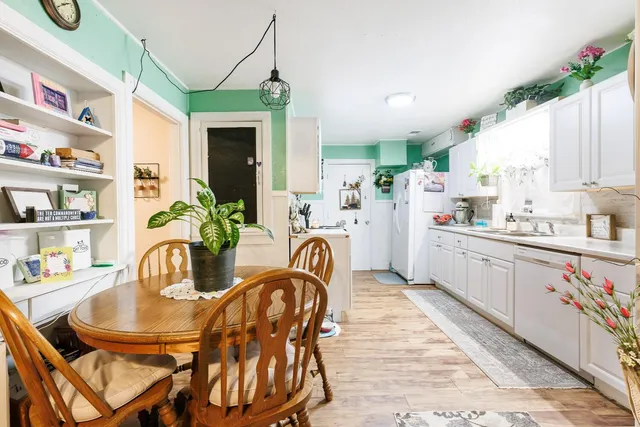 a kitchen with stainless steel appliances granite countertop a dining table chairs stove and white cabinets