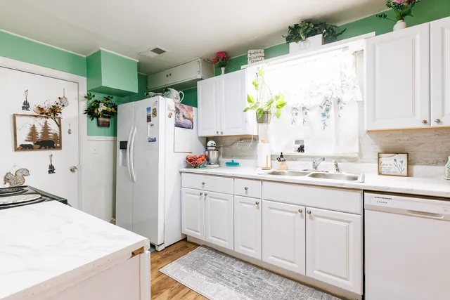 a kitchen with white cabinets and refrigerator