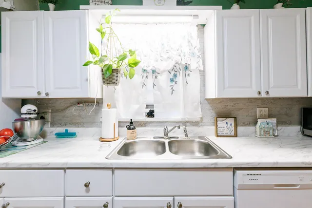 a kitchen with a white sink a window and white stainless steel appliances