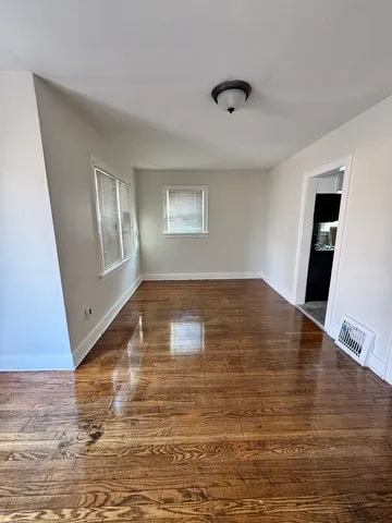 a view of empty room with window and wooden floor