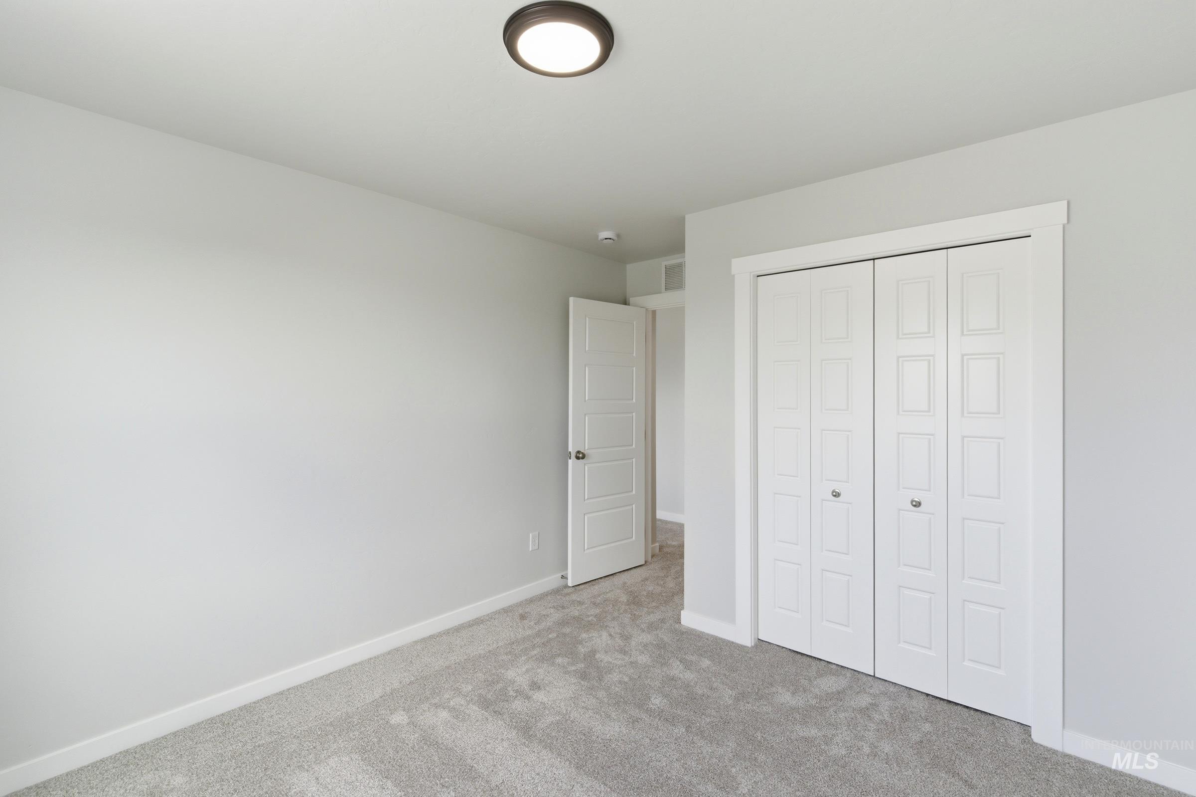 12829 Decatur Street Nampa, ID 83651 - Photo 21 of 33 Spacious room featuring light gray carpeting, white baseboards, and a flush-mount ceiling light fixture