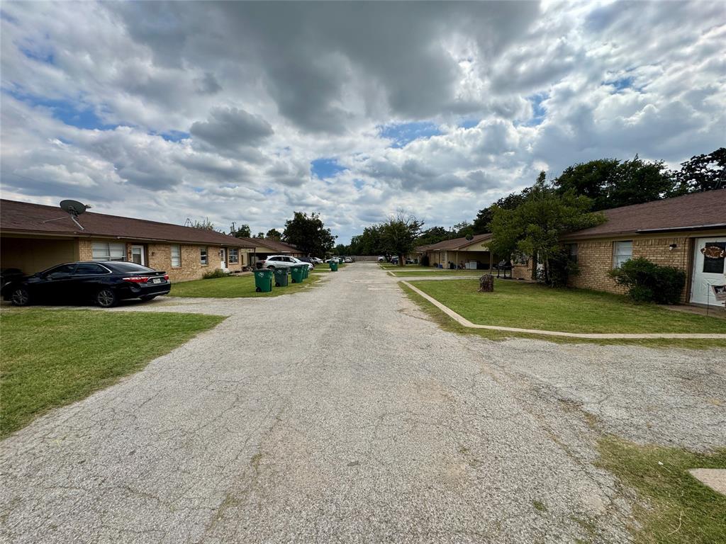 a view of a house with a big yard and a large parking space