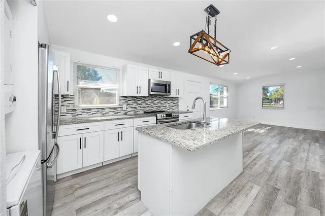 a kitchen with stainless steel appliances granite countertop a sink cabinets and a wooden floor