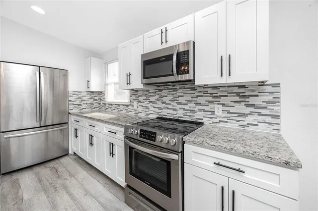 a kitchen with granite countertop a sink stove and refrigerator