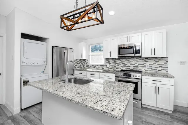 a kitchen with kitchen island granite countertop a sink stove and refrigerator