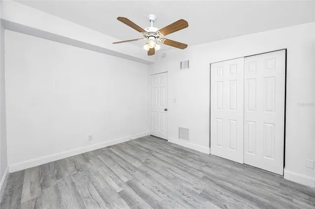 an empty room with wooden floor and ceiling fan