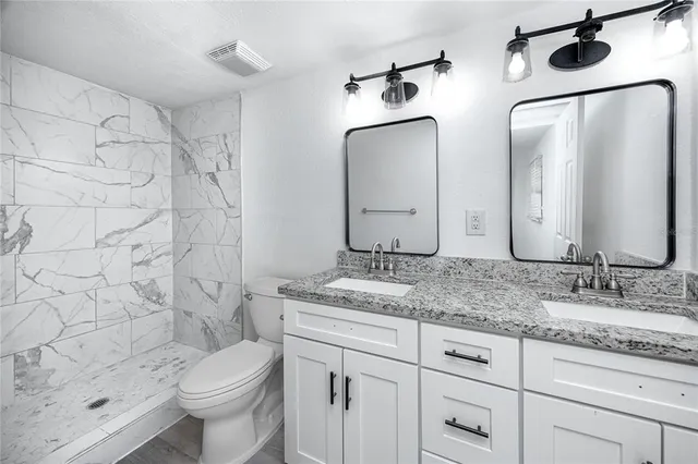 a bathroom with double vanity sink toilet and shower