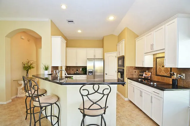 a kitchen with stainless steel appliances kitchen island granite countertop a stove a sink and a refrigerator