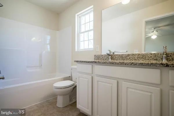 a bathroom with a granite countertop sink toilet and mirror