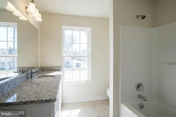 a bathroom with a granite countertop sink a toilet and bathtub