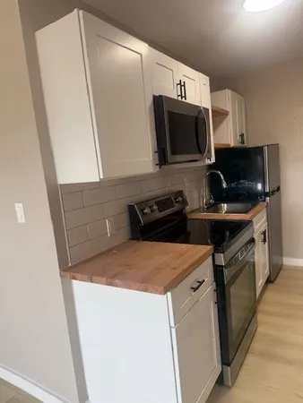a kitchen with stainless steel appliances a stove a microwave a sink and cabinets