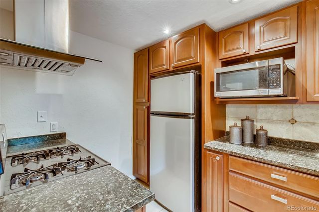 a kitchen with stainless steel appliances granite countertop a refrigerator and a stove top oven