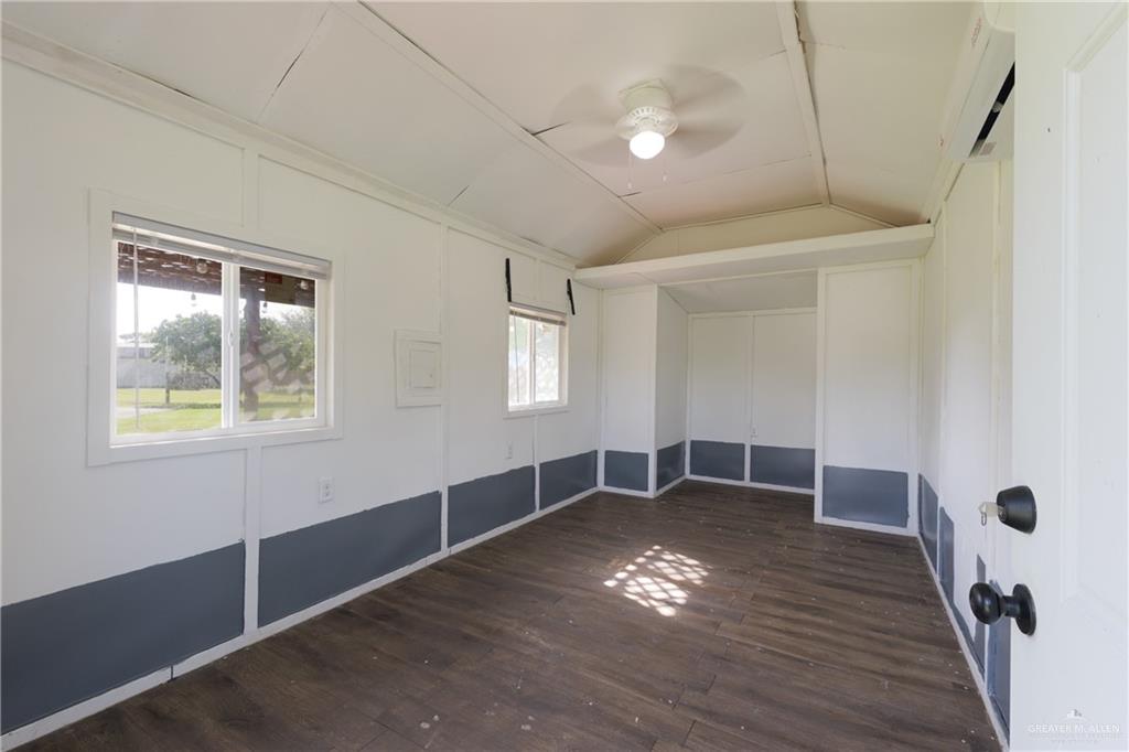 20538 Rio Rancho Road Harlingen, TX 78552 - Photo 14 of 19 Spare room with vaulted ceiling, ceiling fan, dark wood-style flooring, and a wall unit AC