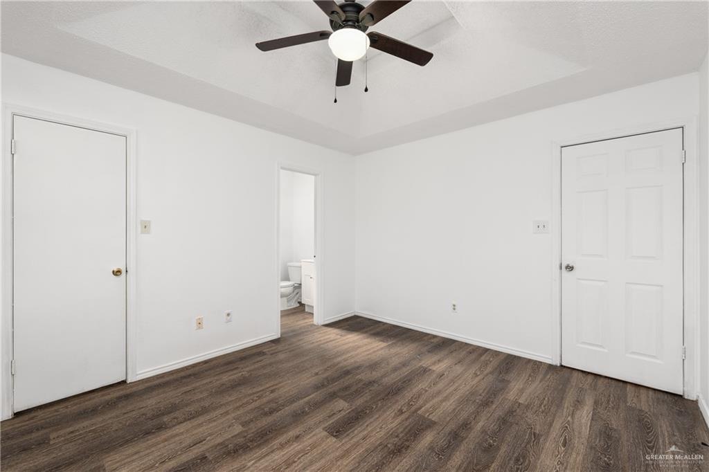 20538 Rio Rancho Road Harlingen, TX 78552 - Photo 4 of 19 Unfurnished bedroom featuring dark wood-style flooring, a raised ceiling, ensuite bath, and a ceiling fan