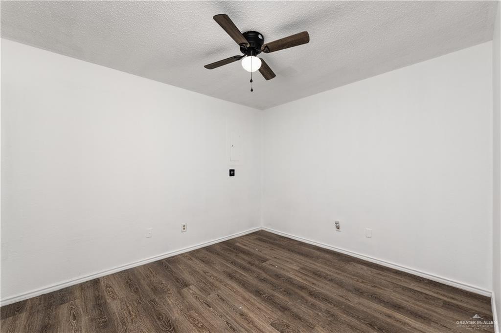 20538 Rio Rancho Road Harlingen, TX 78552 - Photo 9 of 19 Empty room with dark wood finished floors, ceiling fan, and a textured ceiling