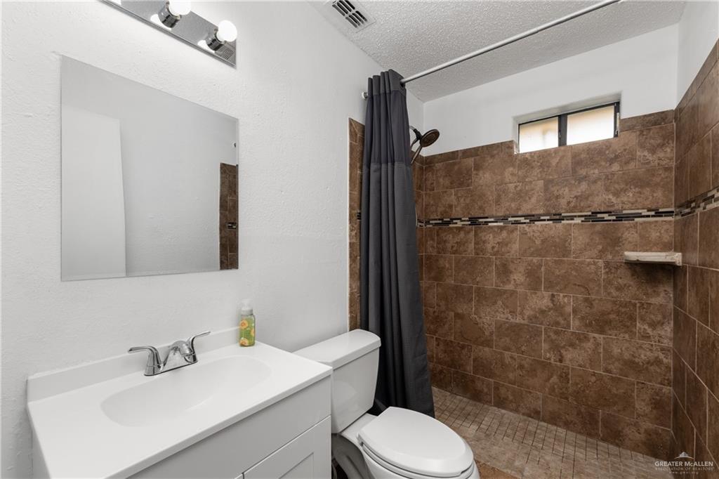 20538 Rio Rancho Road Harlingen, TX 78552 - Photo 10 of 19 Full bathroom with vanity, a tile shower, and a textured ceiling