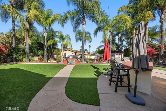 a view of a swimming pool with a patio and palm trees