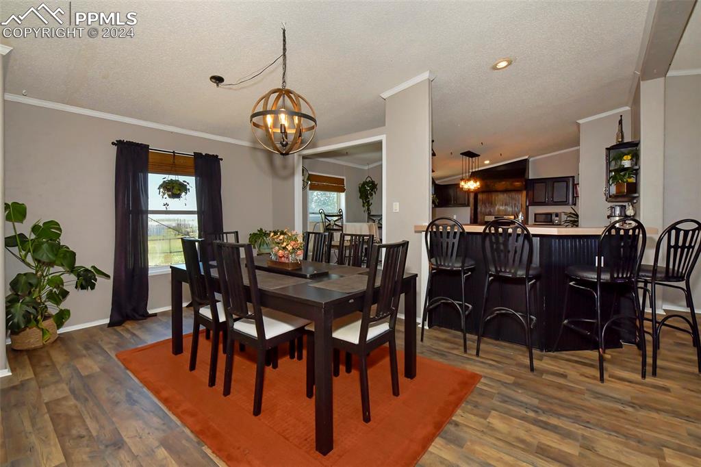 3975 Feather Ridge Drive Peyton, CO 80831 - Photo 15 of 36 a view of a dining room and livingroom with furniture wooden floor a rug a potted plant and a chandelier
