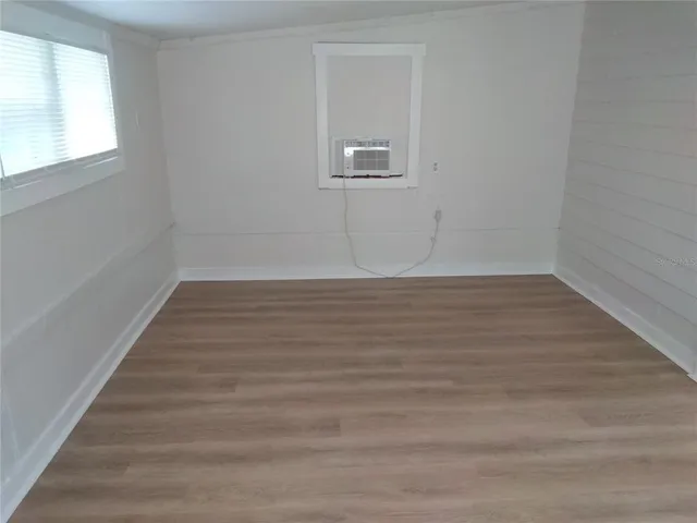 a view of an empty room with wooden floor and a window