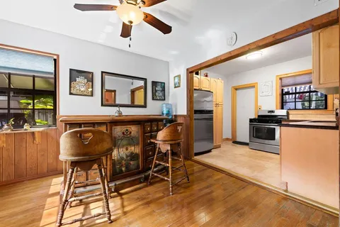 a living room with stainless steel appliances kitchen island granite countertop furniture and a wooden floor
