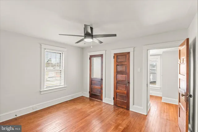 a view of an empty room with wooden floor and a ceiling fan