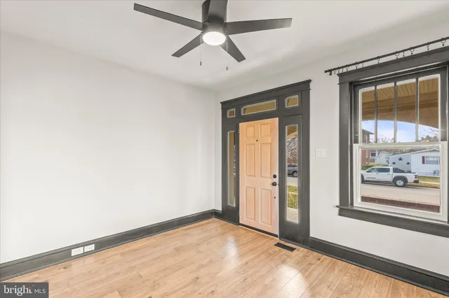 a view of an empty room with wooden floor and fan