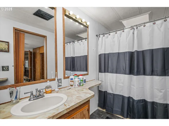 a bathroom with a granite countertop sink a mirror a vanity and a shower
