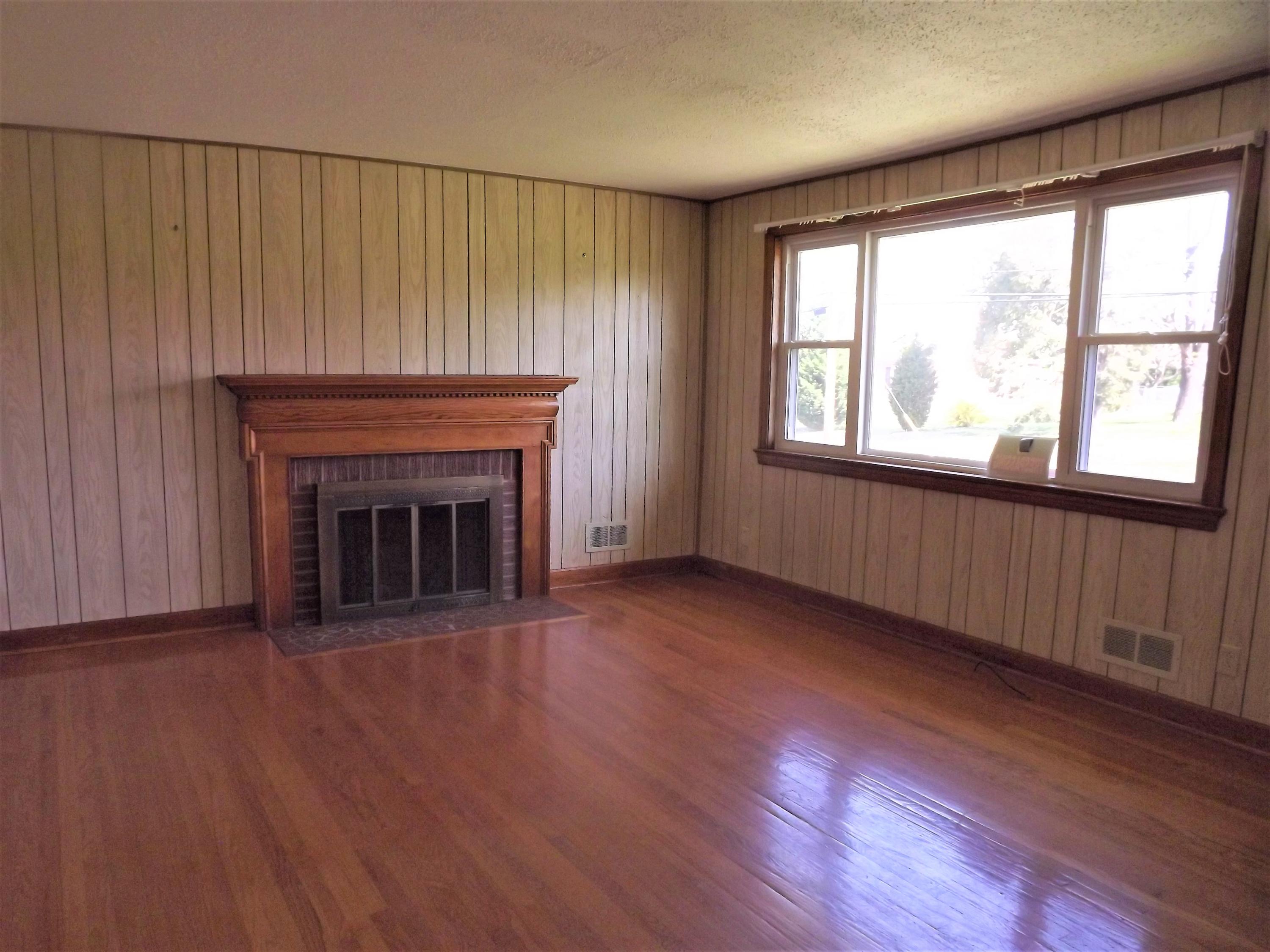 4320 Cove Road Roanoke, VA 24017 - Photo 5 of 10 an empty room with wooden floor fireplace and windows