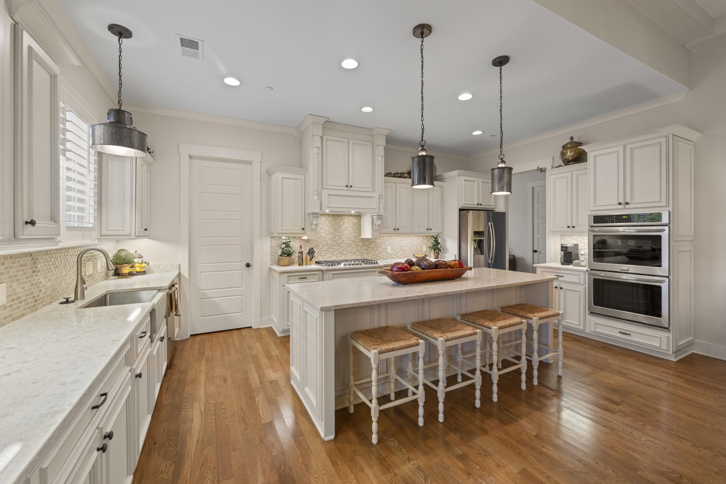 195 Hunters Rest Lane Piperton, TN 38017 - Photo 17 of 36 a kitchen with stainless steel appliances kitchen island granite countertop a wooden floor and white cabinets