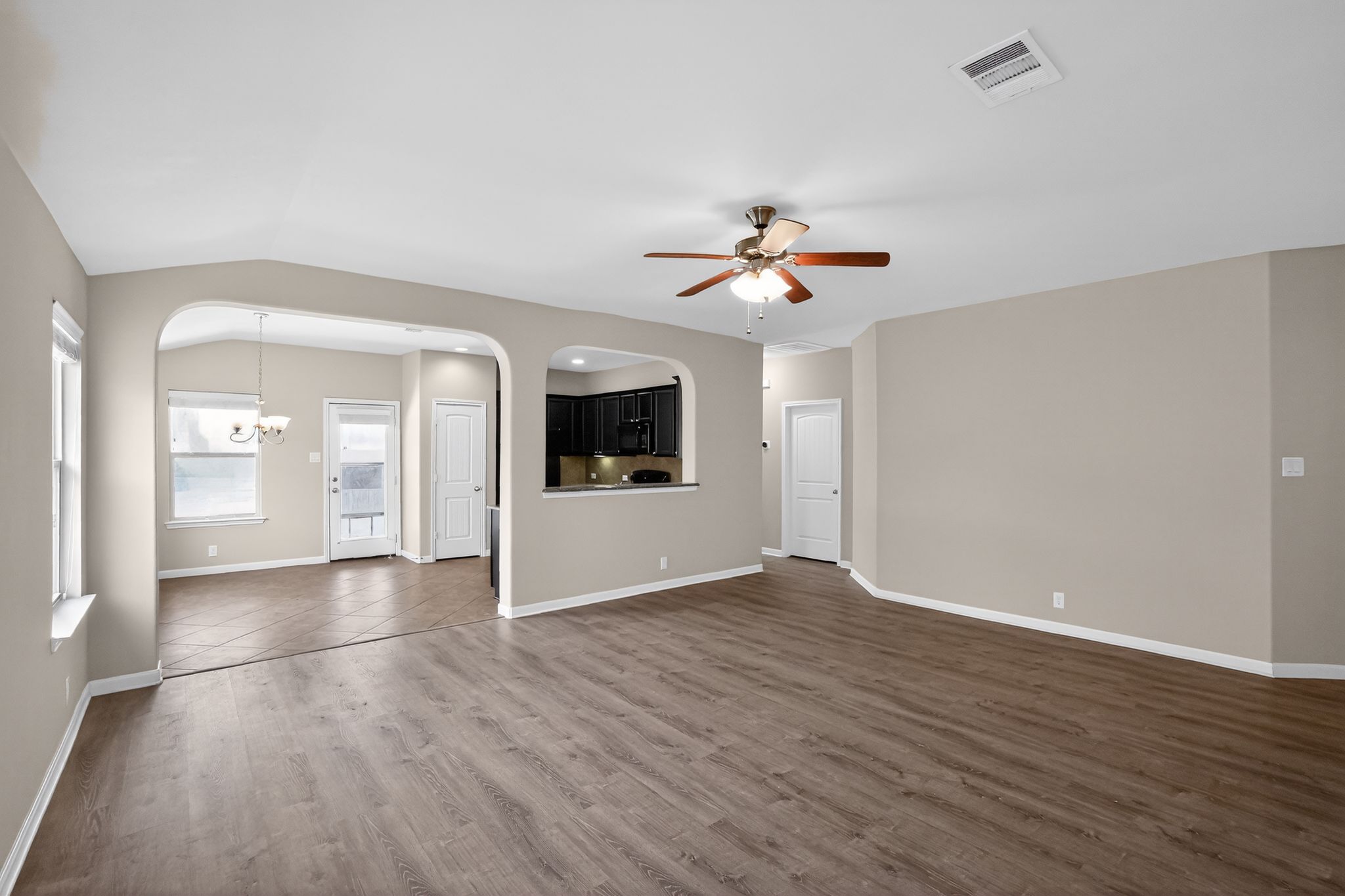 1313 April Meadows Loop Georgetown, TX 78626 - Photo 3 of 21 Unfurnished living room featuring arched walkways, ceiling fan, dark wood finished floors, vaulted ceiling, and suspended lighting