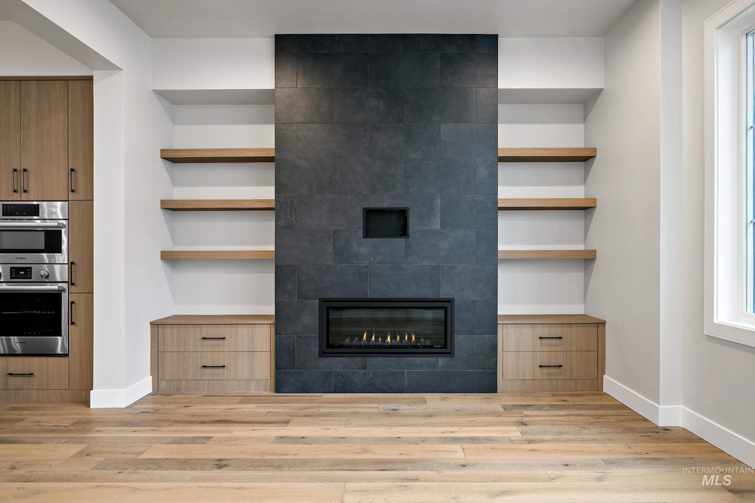 11725 North Rabbitbrush Way Boise, ID 83714 - Photo 11 of 36 Unfurnished living room featuring built in features, a tile fireplace, and light wood-type flooring