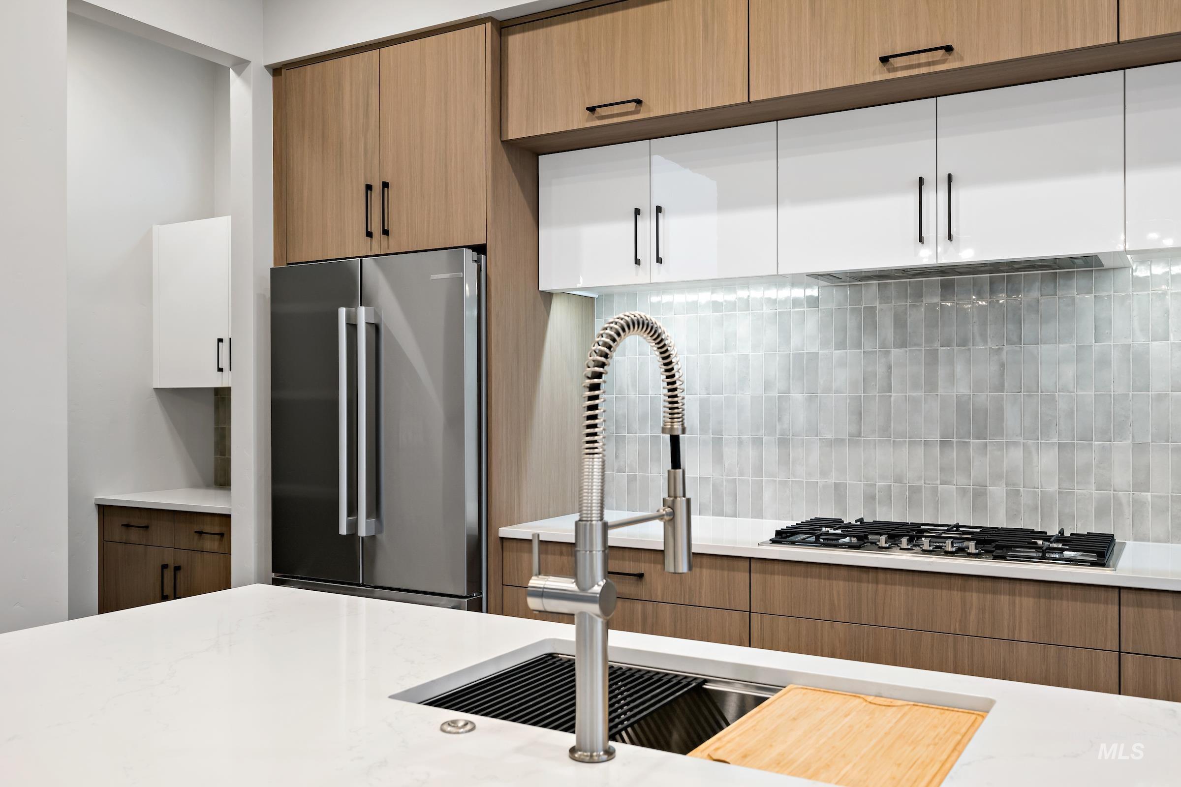 11725 North Rabbitbrush Way Boise, ID 83714 - Photo 16 of 36 Kitchen with stainless steel appliances, brown cabinets, backsplash, and light stone counters