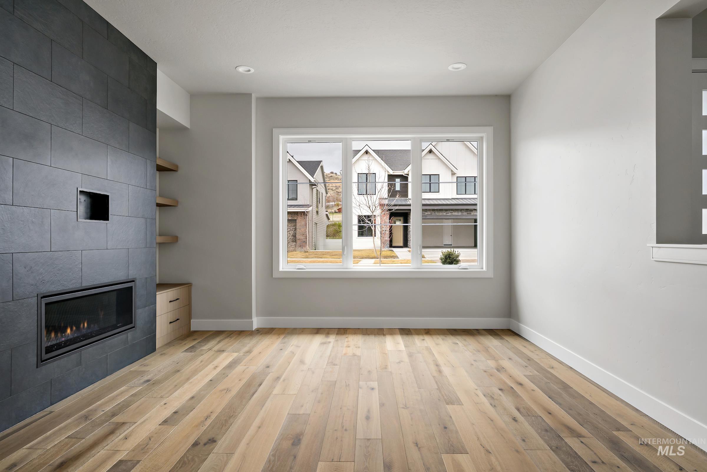 11725 North Rabbitbrush Way Boise, ID 83714 - Photo 4 of 36 Unfurnished living room featuring light wood-style floors and a tile fireplace