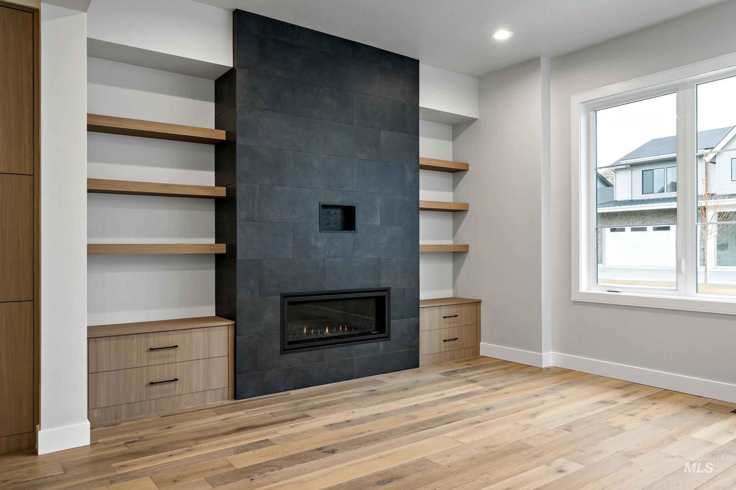 11725 North Rabbitbrush Way Boise, ID 83714 - Photo 6 of 36 Unfurnished living room featuring built in features, a tiled fireplace, light wood-type flooring, and recessed lighting