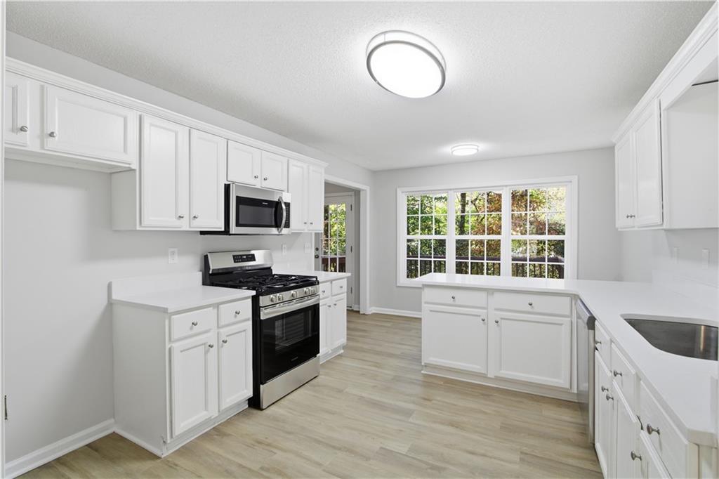 10 Mariner Way Acworth, GA 30102 - Photo 6 of 20 a kitchen with stainless steel appliances granite countertop a stove top oven a sink dishwasher and white cabinets with wooden floor