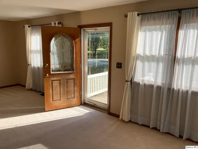 an empty room with windows wooden floor and front door