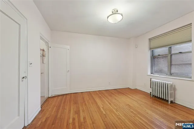 a view of an empty room with a window and wooden floor