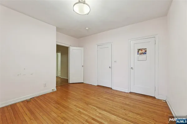 an empty room with wooden floor cabinet and windows