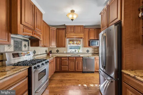 a kitchen with stainless steel appliances granite countertop a stove refrigerator and cabinets