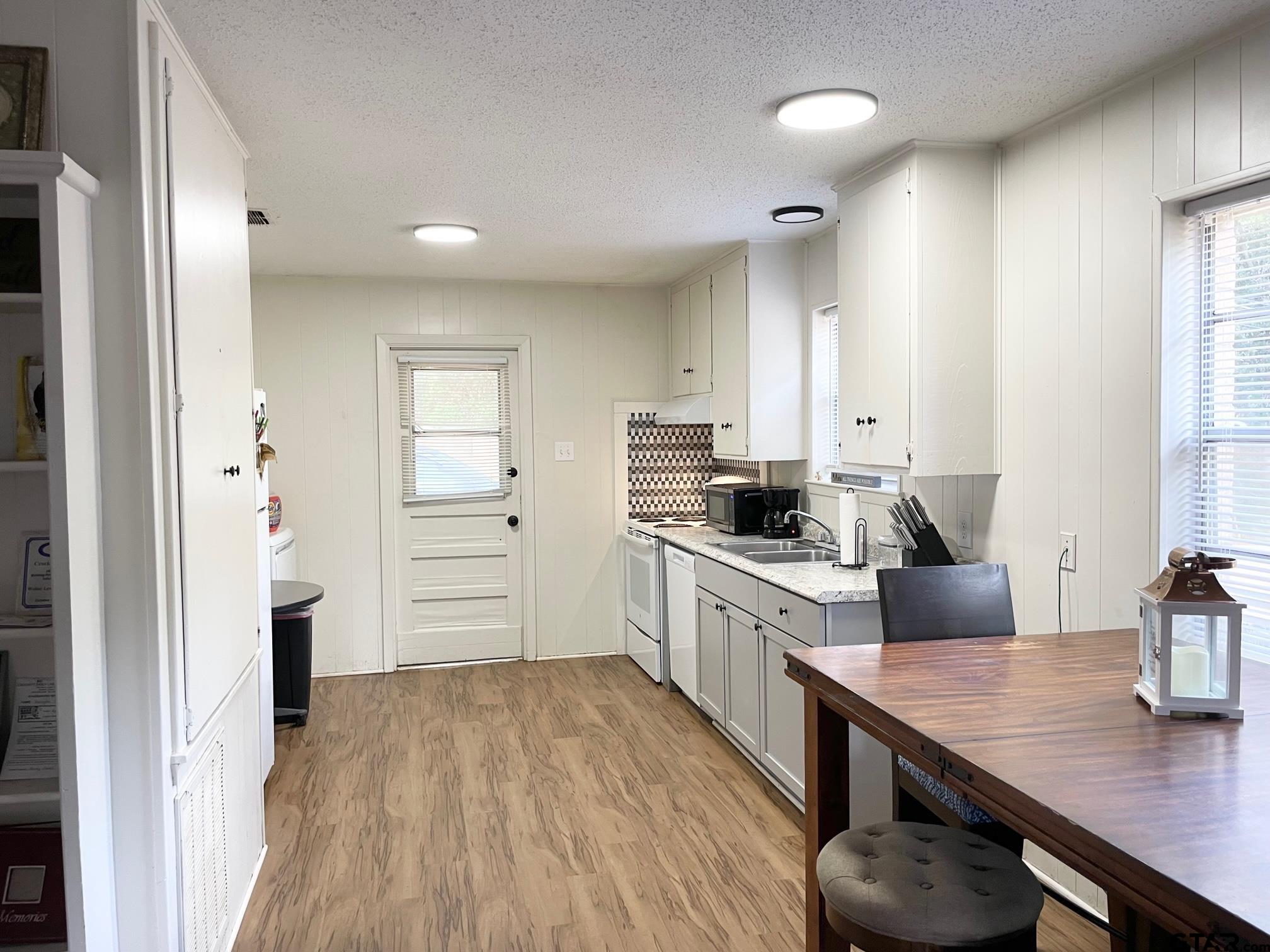 2301 North 6th Street Crockett, TX 75835 - Photo 8 of 12 a kitchen with a wooden floor window and white cabinets