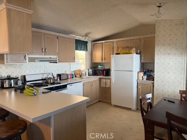 a kitchen with a refrigerator a stove a sink dishwasher a stove and white countertops with wooden floor