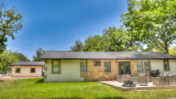 a living room with stainless steel appliances furniture a fireplace and a flat screen tv