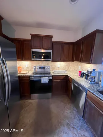 a kitchen with stainless steel appliances a sink dishwasher a stove top oven a refrigerator and cabinets