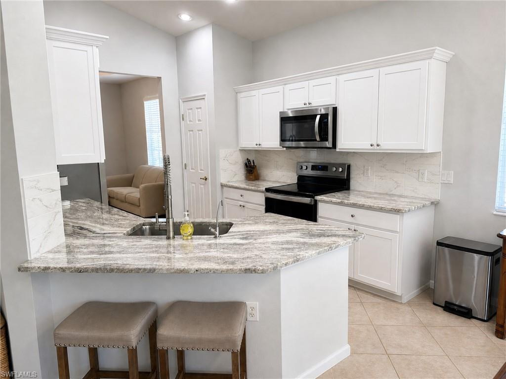 19081 Ridgepoint Drive, Unit 201 Estero, FL 33928 - Photo 4 of 42 a kitchen with stainless steel appliances granite countertop a stove a sink and a refrigerator