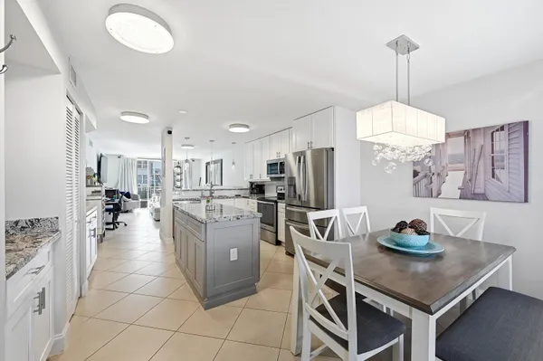 a kitchen with stainless steel appliances granite countertop a stove refrigerator a dining table and chairs with wooden floor