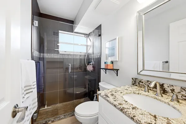 a bathroom with a sink a toilet and shower