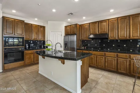 a kitchen with stainless steel appliances granite countertop wooden cabinets a stove a sink and a oven