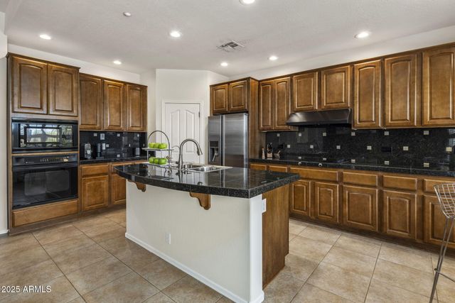 a kitchen with stainless steel appliances granite countertop wooden cabinets a stove a sink and a oven