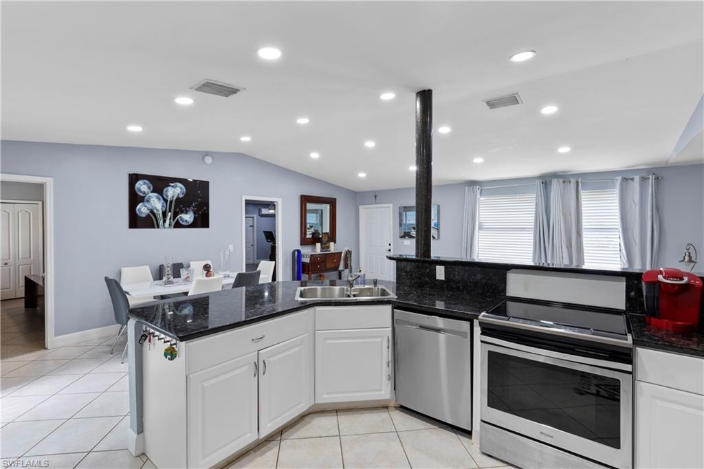 4641 Pine Ridge Road Naples, FL 34119 - Photo 18 of 30 a kitchen with granite countertop sink cabinets and stainless steel appliances